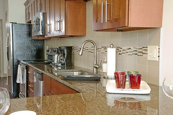 A kitchen with a black fridge and brown cabinets.